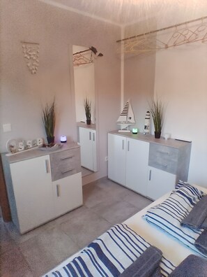 Een moderne, goed verlichte kamer met een bank, een model zeilboot en potplanten.