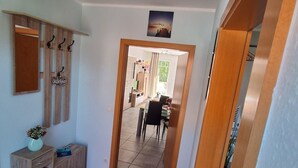 Käytävä, jossa on puinen kaappi, musta matto ja ovi, joka johtaa ruokailutilaan.