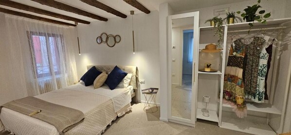 Ein Schlafzimmer mit einem Bett, einem Kleiderschrank, einem Spiegel und einer Tür zu einem anderen Raum.