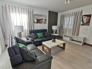 A modern living room with a sofa, coffee table, and decorative items. - Holiday Home “Cactus” with Sea View, Wi-Fi and Air Conditioning (Yaiza)