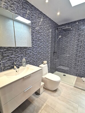A modern bathroom with a large mirror, a white sink, a toilet, and a shower area. - Holiday Home “Cactus” with Sea View, Wi-Fi and Air Conditioning (Yaiza)