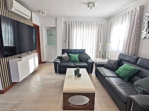 A modern living room with a flat-screen TV, two sofas, a coffee table, and a lamp. - Holiday Home “Cactus” with Sea View, Wi-Fi and Air Conditioning (Yaiza)