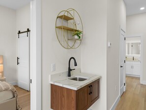 Een badkamer met een witte wastafel, een houten kast en een spiegel met een gouden lijst.