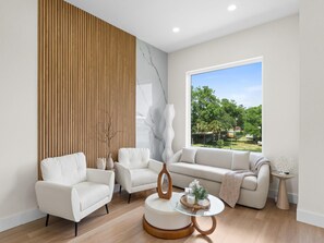 Ein modernes Wohnzimmer mit großem Fenster, einer Wand aus Holzleisten und einer Wand mit Marmorverkleidung.