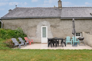 A rustic building with a tiled patio, outdoor seating, and a barbecue grill. - 'Gîte de Keravy - 4 guests - Vannes' with terrace, shared garden and Wi-Fi (Vannes)