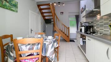 A dining area with a table set for four, a kitchen with modern appliances, and a staircase leading to another level.
