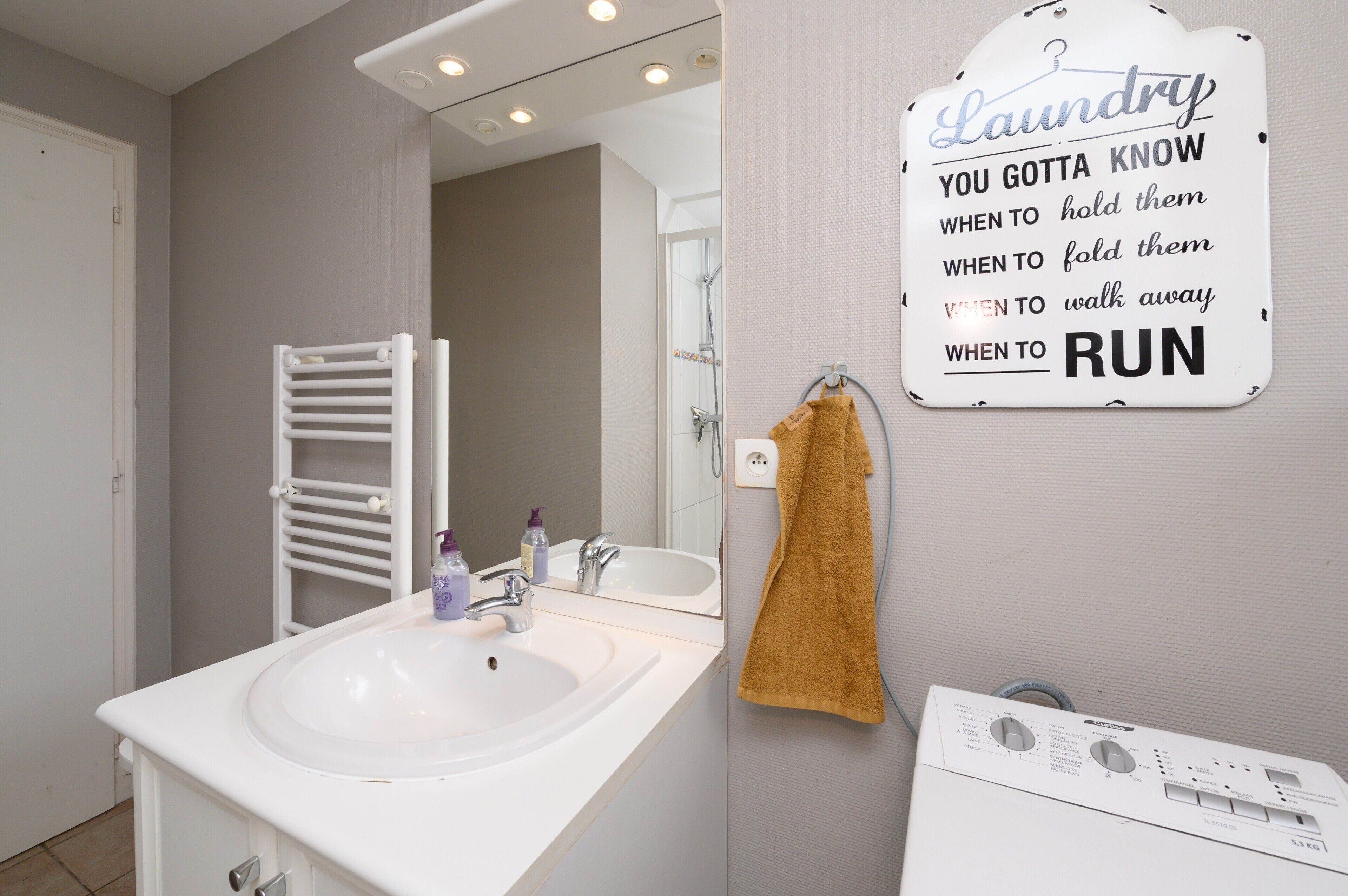 Een badkamer met een wit wastafelmeubel, spiegel en handdoekhouder.