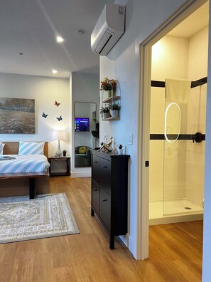 A modern bedroom with a bed, bedside table, lamp, and a TV. - Forest Breeze Studio, Downtown with King Bed (Halifax)