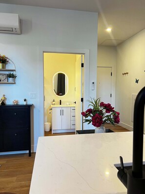 Uma cozinha moderna com armários brancos, bancada de mármore e um vaso de flores.