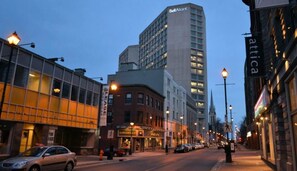 A city street with a tall hotel, a restaurant, and a store with a sign that says 'attica'. - Forest Breeze Studio, Downtown with King Bed (Halifax)