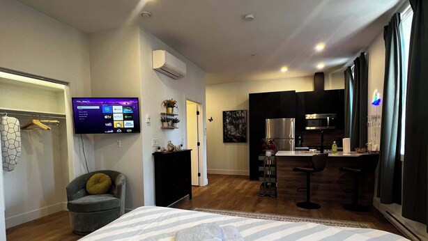 Ett hotellrum med en säng, en tv som är monterad på väggen, ett litet kök och en sittgrupp.