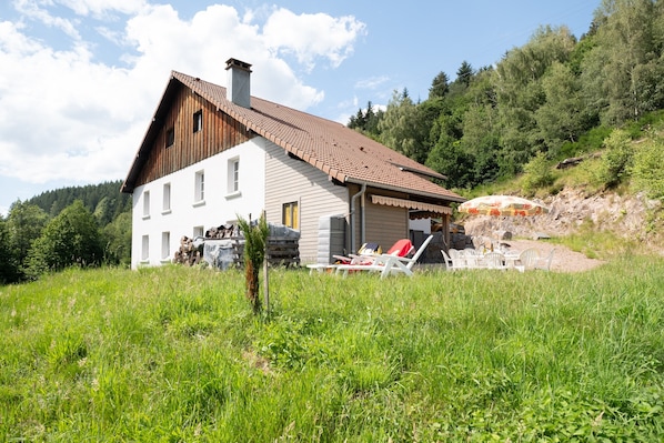 A house with a sloped roof, a chimney, and a small porch with outdoor furniture.