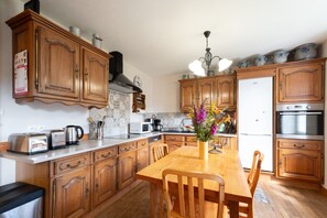 Una cocina con armarios de madera, una mesa de comedor, un refrigerador y un microondas.