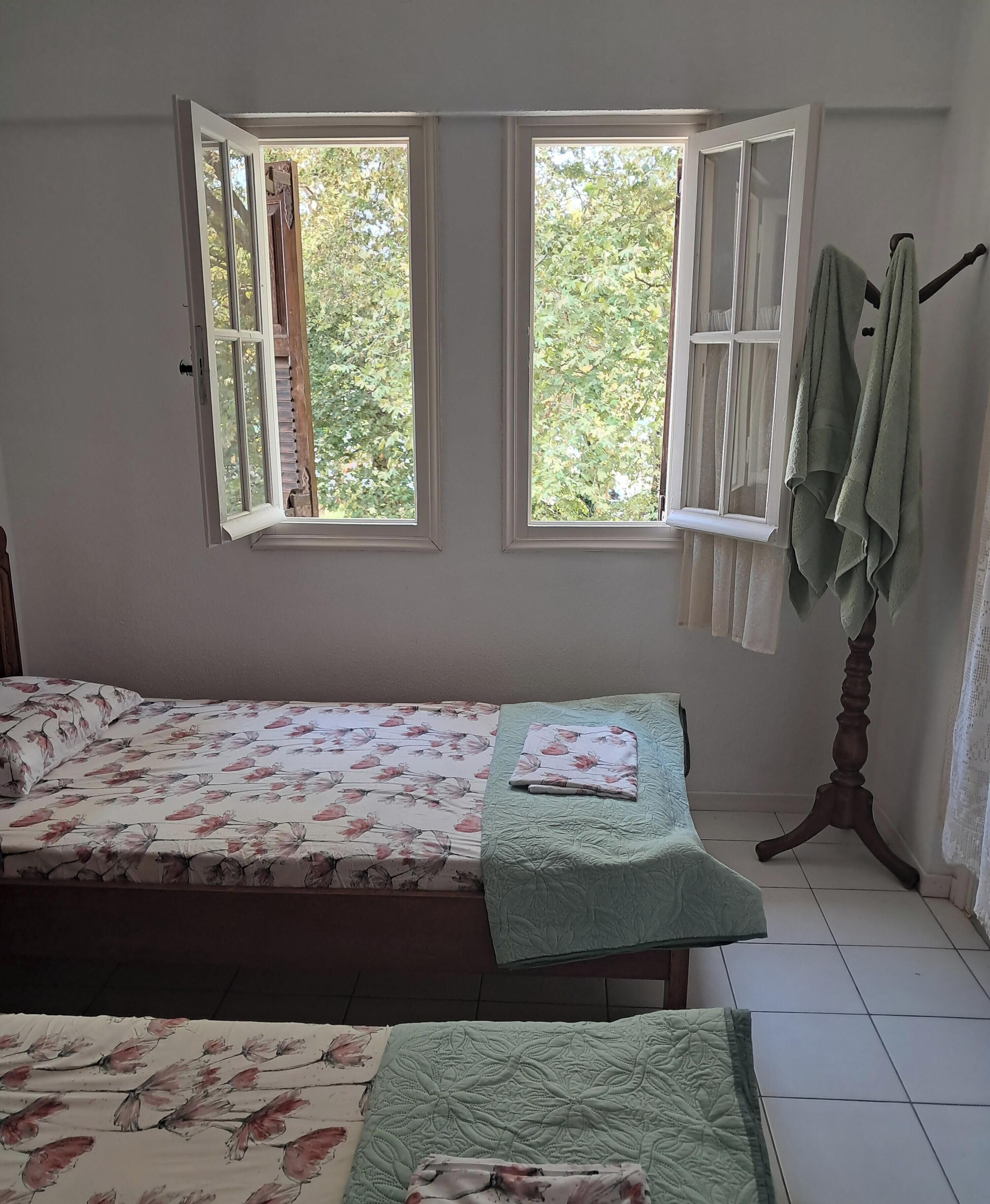 A bedroom with a bed, a window, and a wooden table.