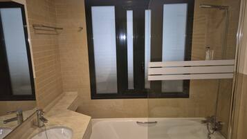 A bathroom with two sinks, a bathtub, and a shower.