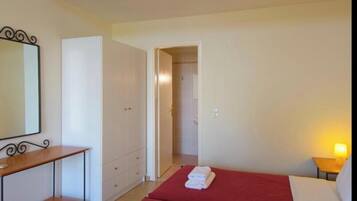 A hotel room with a bed, a desk, a wardrobe, and a bathroom visible through an open door.