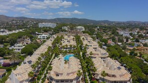 A residential area with multiple buildings, a central swimming pool, and surrounding greenery. - 3160 Elegant Seafront House (Marbella)