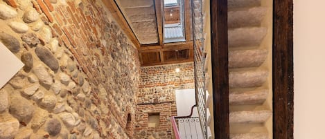 A stone-walled corridor with a wooden staircase and a fire extinguisher.
