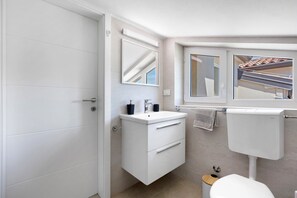 Un baño moderno con inodoro, lavamanos, espejo y ventana.