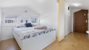 A bedroom with a bed, a window, a door, and a wooden floor. - Holiday Home 'Seaview Apartment Poreć Umgebung' with Sea View and Air Conditioning (Tar)