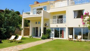 Une maison à deux étages avec un balcon, une pelouse et du mobilier d’extérieur.