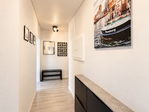 Ein Flur mit gerahmten Bildern, einer Bank, einem an der Wand befestigten Schrank und einem großen Poster eines Bootes.