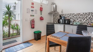 A compact kitchen with a dining area, a fire extinguisher, and a view of a garden. - Apartment 'Pool  View' with Shared Pool, Shared Garden and Wi-Fi (Gaula)