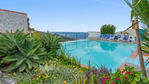 A pool with blue chairs, surrounded by plants and flowers. - Apartment 'Pool  View' with Shared Pool, Shared Garden and Wi-Fi (Gaula)