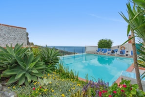A pool with blue chairs, surrounded by plants and flowers. - Apartment 'Pool  View' with Shared Pool, Shared Garden and Wi-Fi (Gaula)