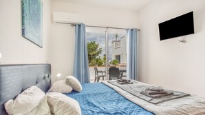 A bedroom with a bed, a flat-screen TV, and a view of an outdoor area. - Apartment 'Pool  View' with Shared Pool, Shared Garden and Wi-Fi (Gaula)