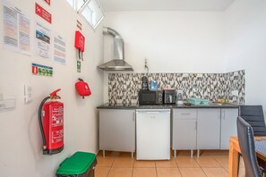 A compact kitchen with a microwave, coffee maker, and a small refrigerator. There is a fire extinguisher mounted on the wall and a green trash bin. - Apartment 'Pool  View' with Shared Pool, Shared Garden and Wi-Fi (Gaula)