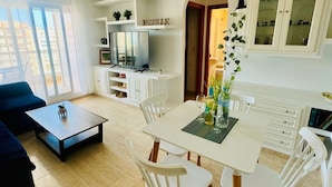 Una sala de estar moderna con comedor, ventilador de techo, televisor y vista al exterior.