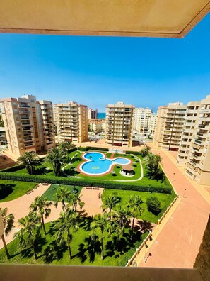 Zona residencial con edificios altos, piscina central y zonas verdes cuidadas.