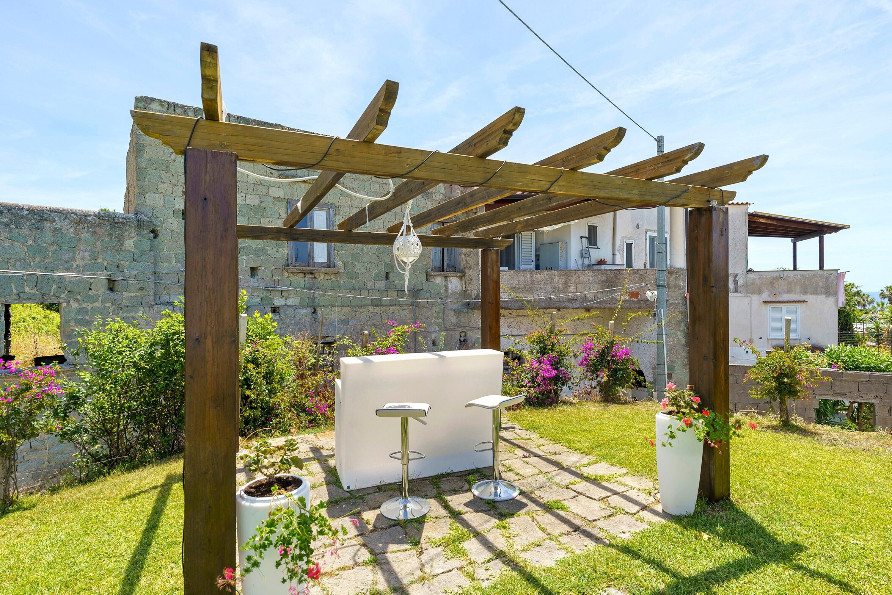 Un patio jardín con pérgola, muebles de exterior y plantas en macetas.