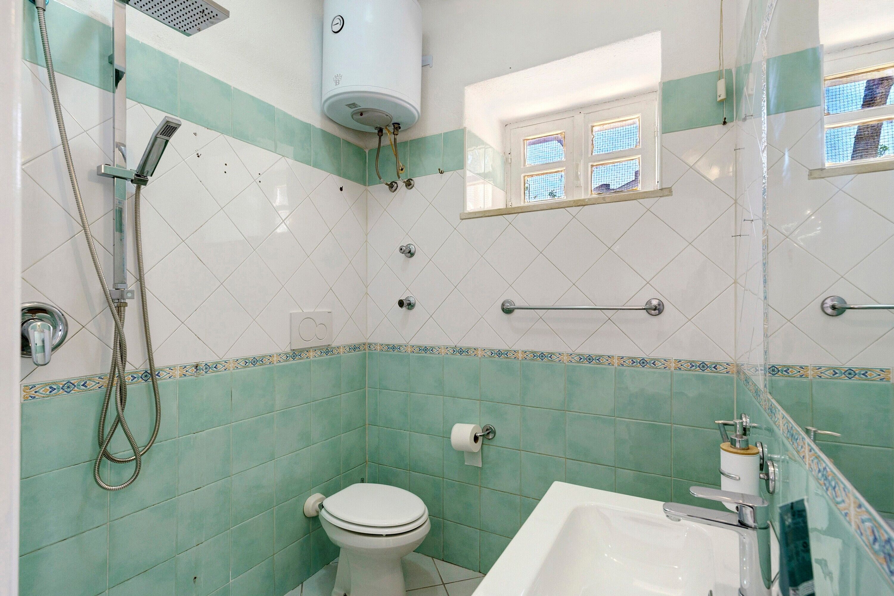 A bathroom with a toilet, a shower, a bathtub, and a window with a view.