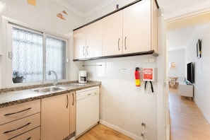 A kitchen with a granite countertop, a coffee maker, and a dishwasher.