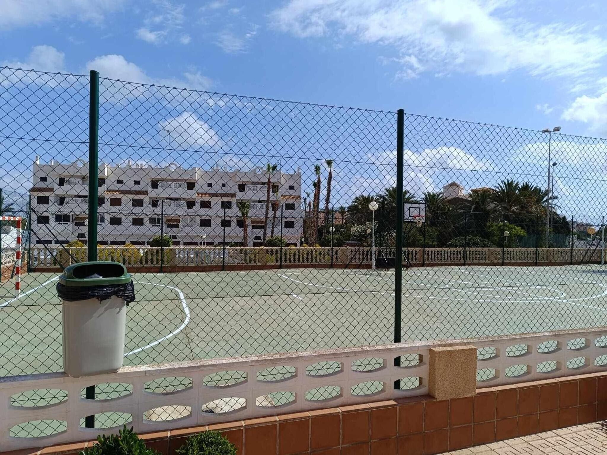 A fenced outdoor basketball court with a building in the background.