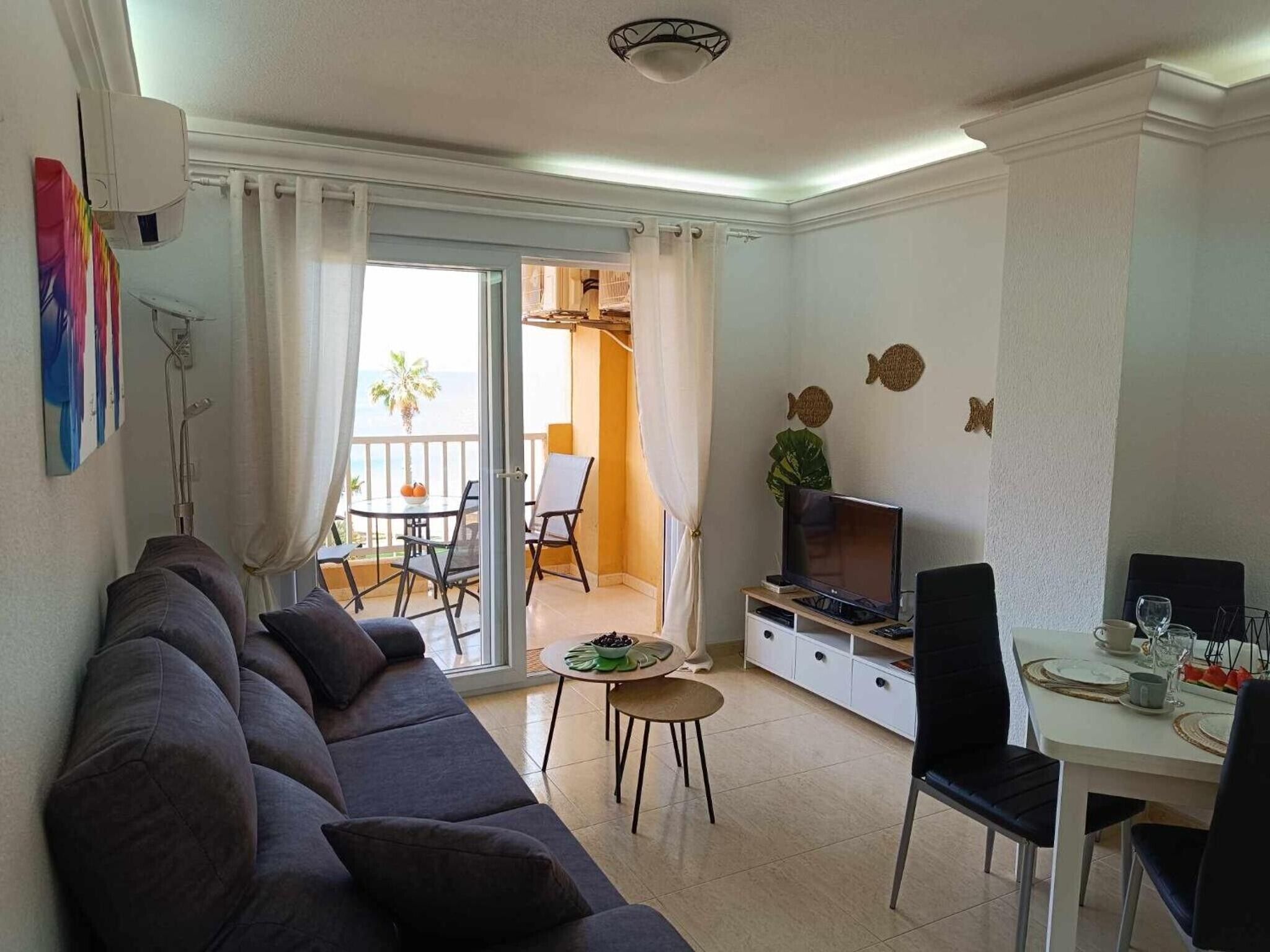Un salon comprenant un canapé, un téléviseur, une table à manger et un balcon avec vue.