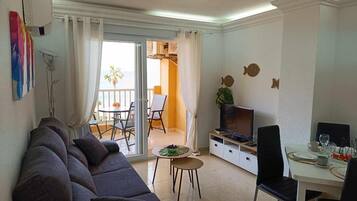 Un salon comprenant un canapé, un téléviseur, une table à manger et un balcon avec vue.