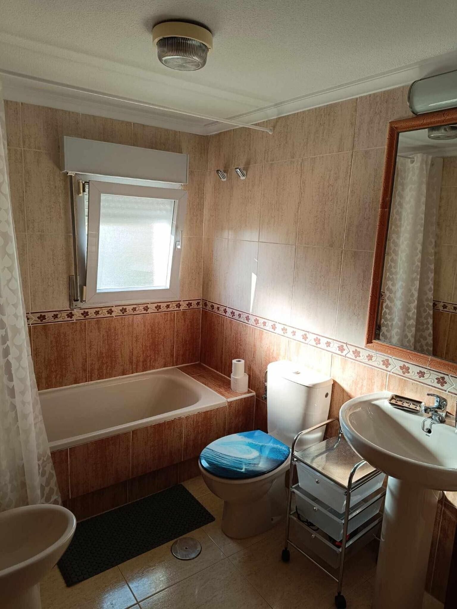 Ein Badezimmer mit Badewanne, Toilette, Waschbecken und einem Fenster.