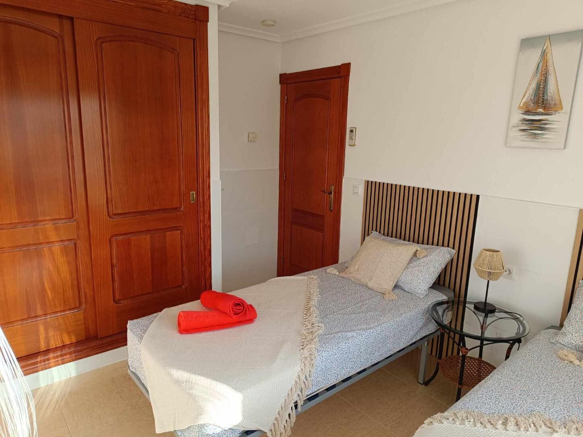 Une chambre à coucher avec un lit, une table de chevet, une lampe et des armoires en bois.