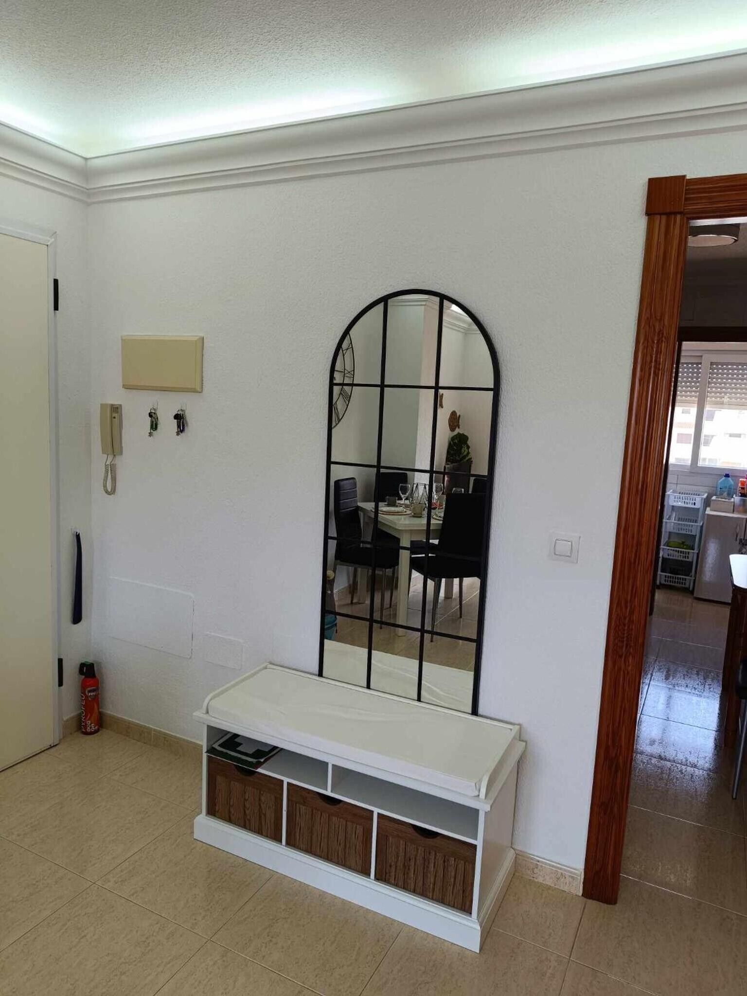 A room with a large mirror, a small table, and a bench with storage.