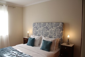 Une chambre à coucher avec un lit, deux tables de chevet et une commode.