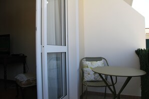 Une pièce avec une porte, une chaise, une petite table et un téléviseur.