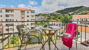 Un balcon avec deux chaises, une table et une vue sur une ville située sur une colline.