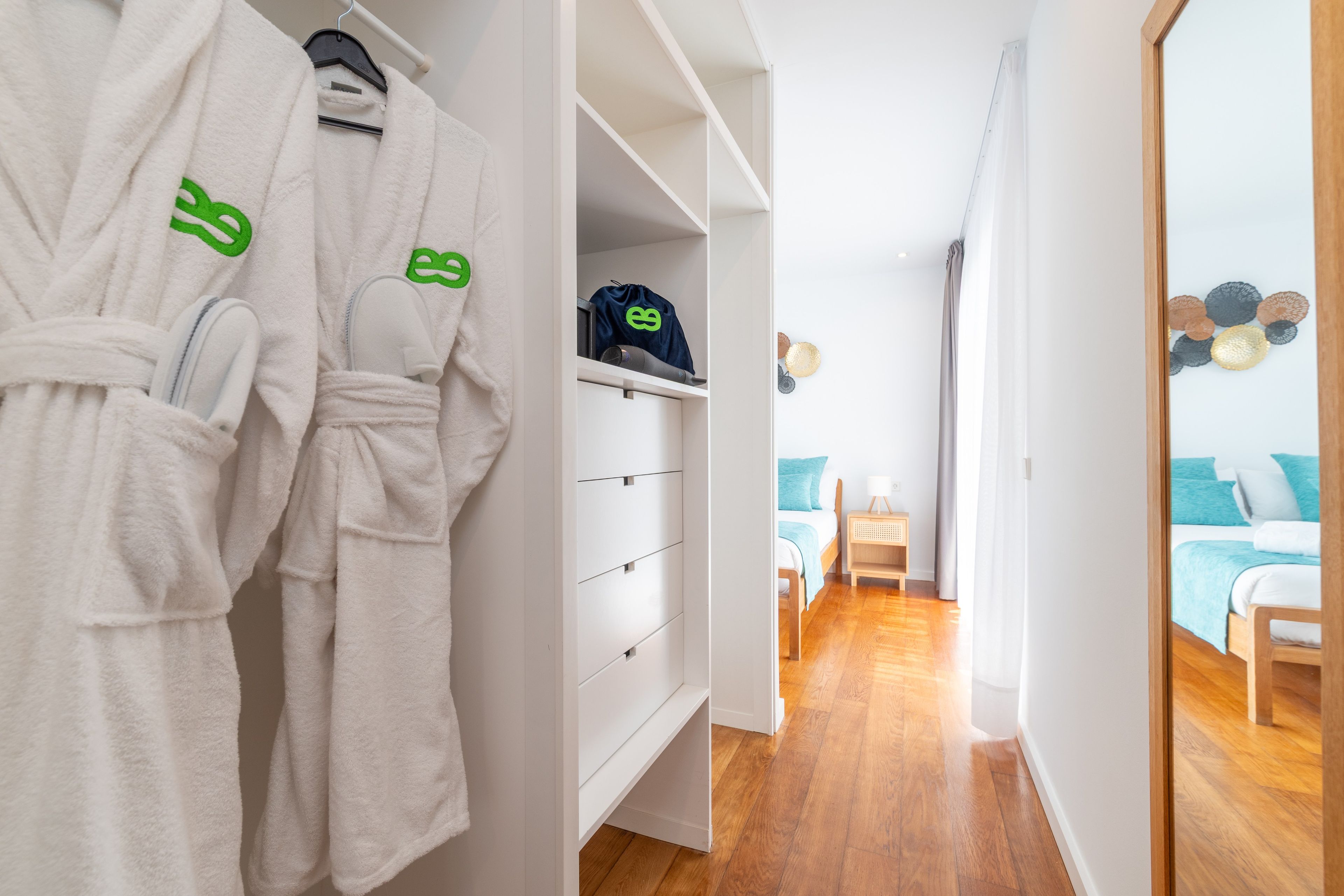 Una habitación de hotel con un armario, una cama con ropa de cama azul y suelo de madera.