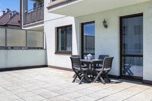 Un patio con una mesa y sillas, una ventana con persianas y un balcón con barandilla.