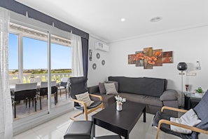 Un salon moderne comprenant un canapé, des fauteuils, une table basse et un coin repas avec des chaises et une table.