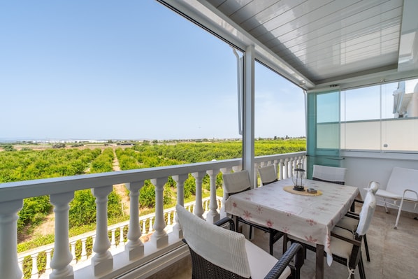 Un balcon avec une table et des chaises, donnant sur un vignoble.
