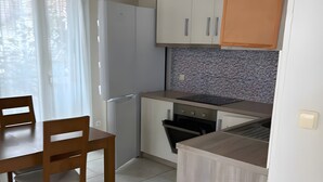 A compact kitchen with a dining area, featuring cabinets, a countertop, and a dining table with chairs. - Apartment 'By The Sea 2' with Private Garden (Meganisi)